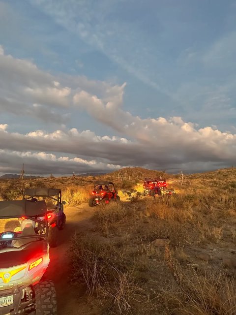 Sand buggies driving through the Sonoran Desert at dusk