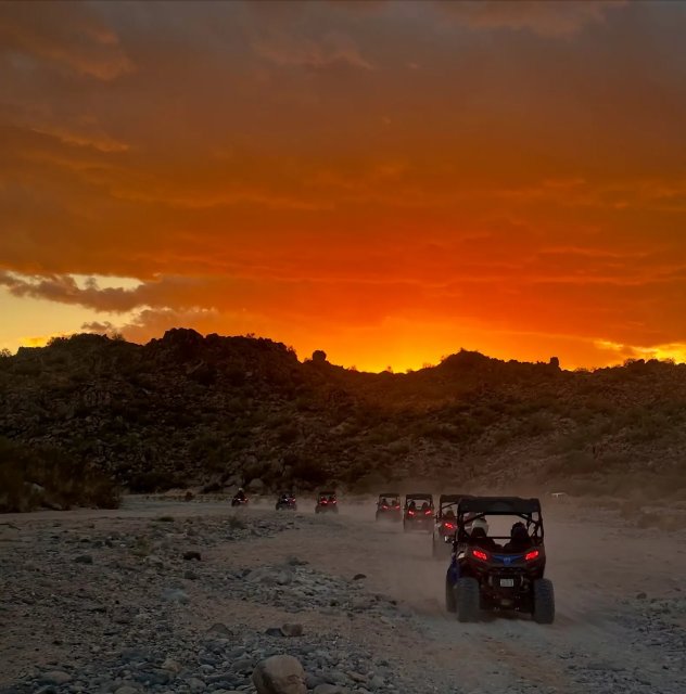Sand buggies silhouetted against a fiery Sonoran Desert sunset